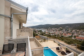 Un balcon avec une piscine, une vue sur la ville et un ciel dégagé.