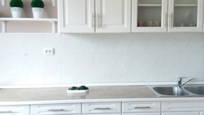 A kitchen with white cabinets, a countertop, and a sink. - Apartments Mirjana (Marina)