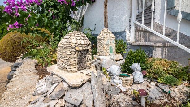 A garden with stone structures, a staircase, and purple flowers. - Apartments Mirjana (Marina)
