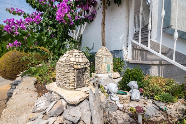 Un jardin agrĂ©mentĂ© de structures en pierre, dâun escalier et de fleurs violettes.