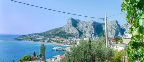 A coastal town with a prominent rocky mountain, a marina with boats, and residential buildings.