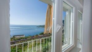 A balcony with a view of the sea and a distant shoreline. - Apartment and Rooms Tatijana (Omis)