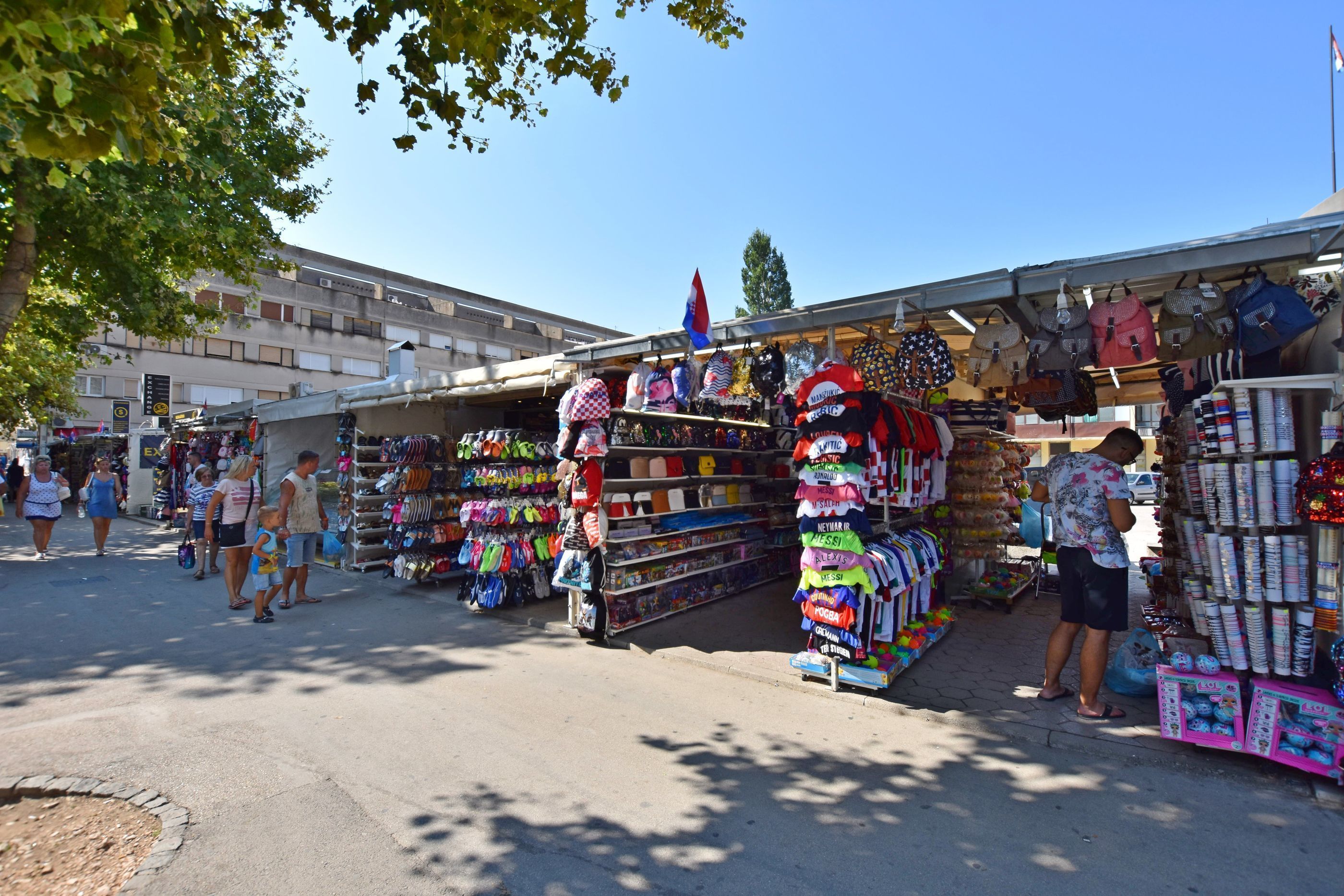 Un marché de rue où l’on trouve différents étals vendant des chapeaux, des sacs et d’autres accessoires.
