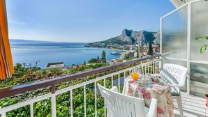 A balcony with a table set for two, overlooking a coastal town and the sea. - Apartment and Rooms Tatijana (Omis)