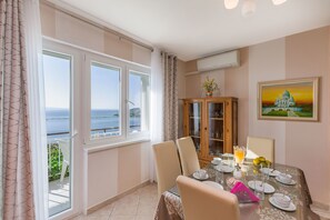 Enjoy meals with a view of the sea from this dining area, featuring a large table and comfortable seating for four.