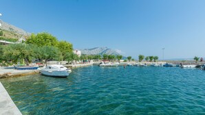 Una marina con barcos amarrados, agua cristalina y montañas al fondo.