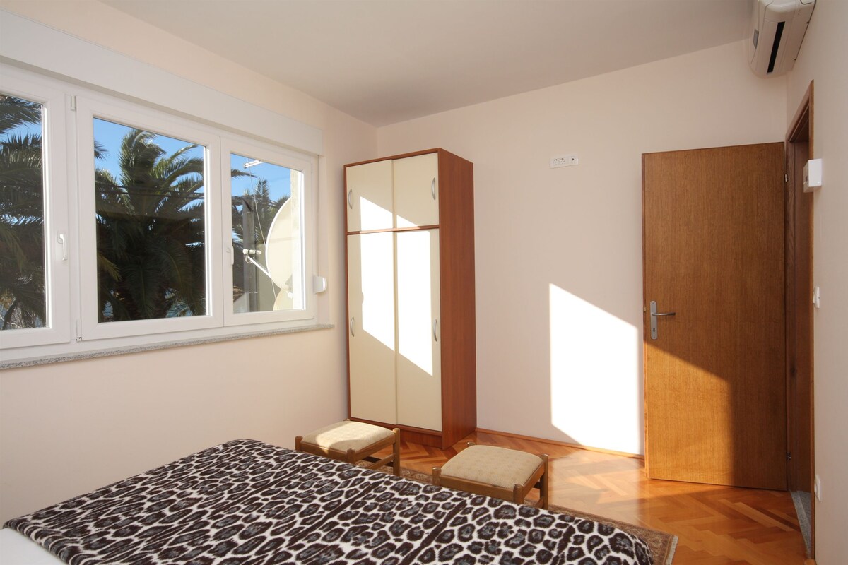 A bedroom with a bed, a wardrobe, a chair, a window, and a door.