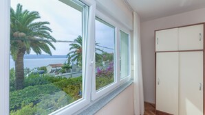 Una habitación con un ventanal grande, un armario y vistas al mar y al verdor.