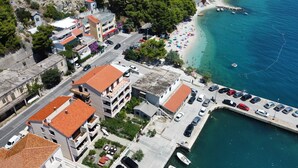 Vista aérea de un pueblo costero con edificios, una playa y un puerto deportivo.