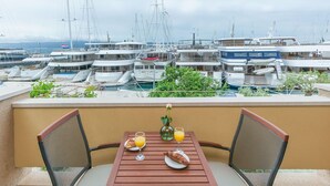 Balcón con una mesa dispuesta para el desayuno, con vistas a un puerto deportivo lleno de yates.