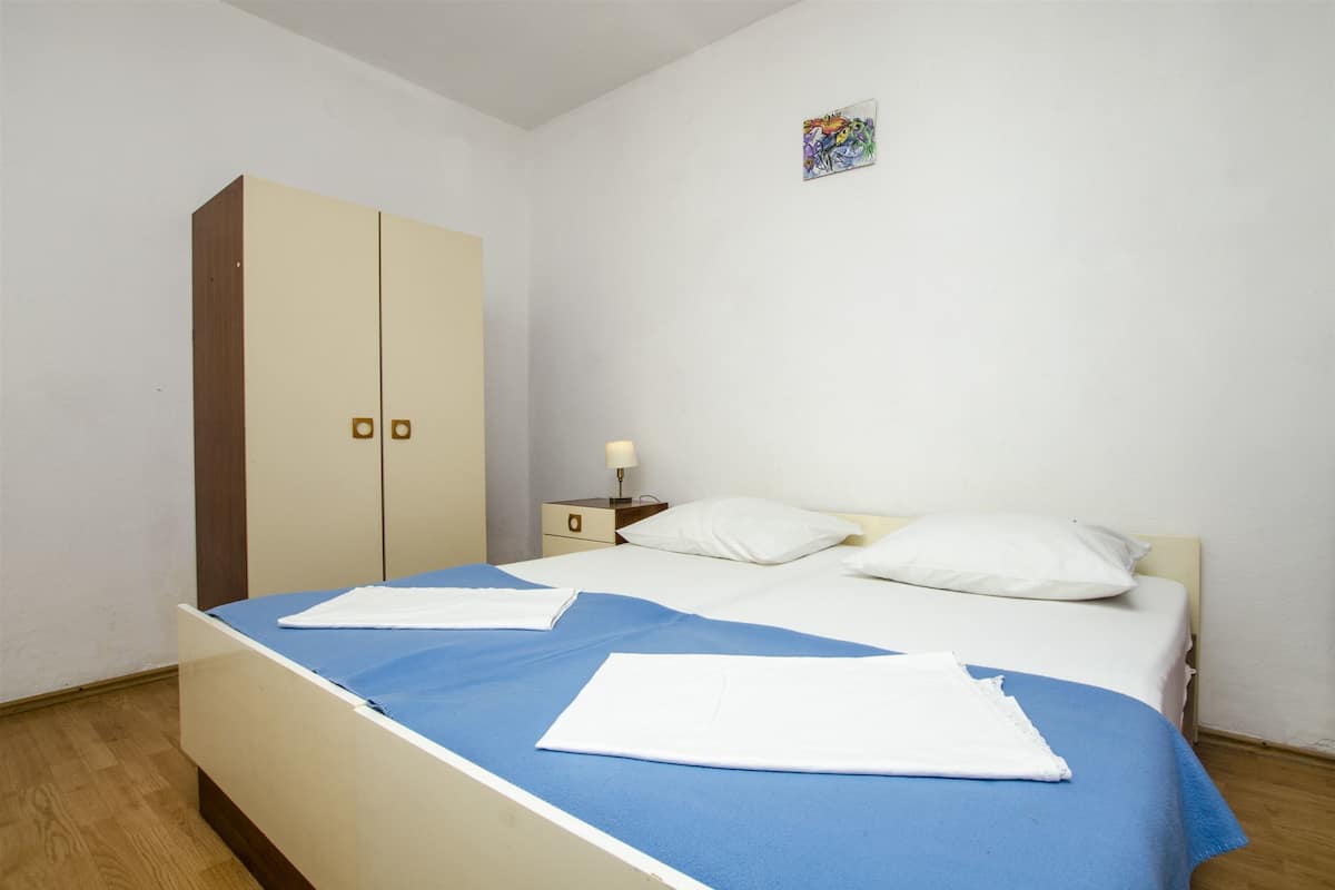 Une chambre à coucher comprenant un lit, une armoire, une table de chevet et une œuvre d’art accrochée au mur.