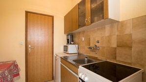 Una cocina compacta con armarios de madera, un microondas, un lavamanos y una estufa.