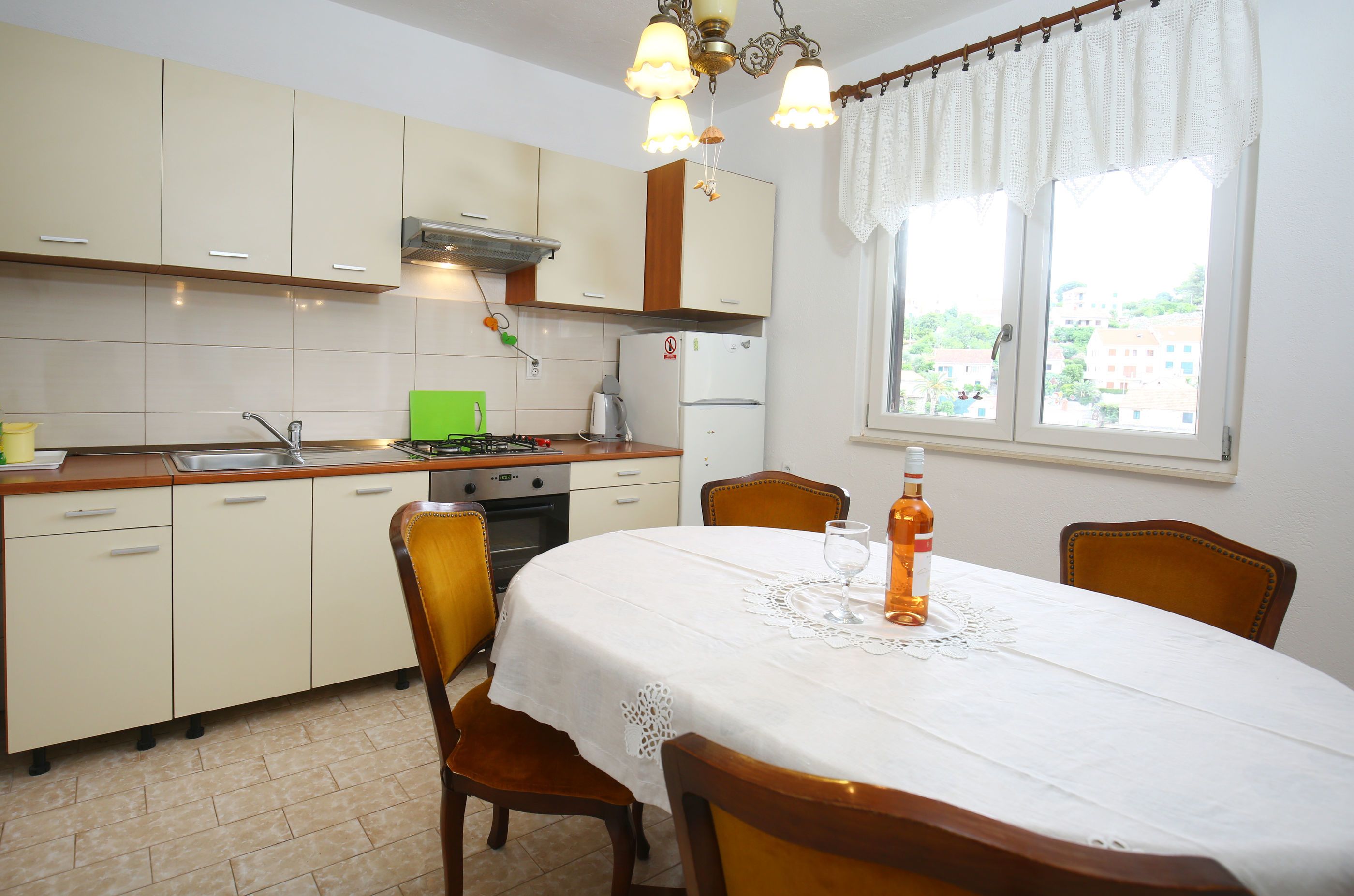 Una cocina con una mesa de comedor para dos personas, un refrigerador y una ventana con vistas a edificios.