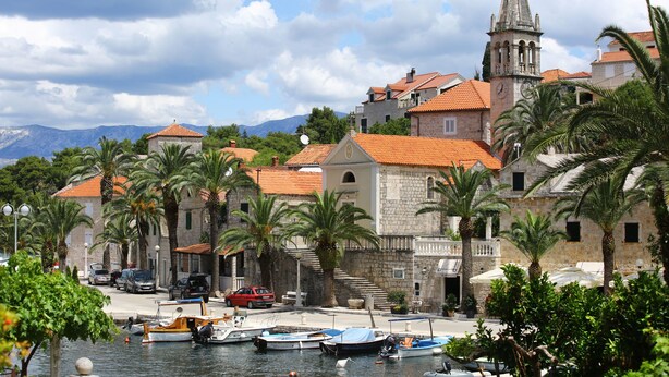 A coastal town with historic stone buildings, a church tower, and a marina with boats. - Apartments Boro (Splitska)