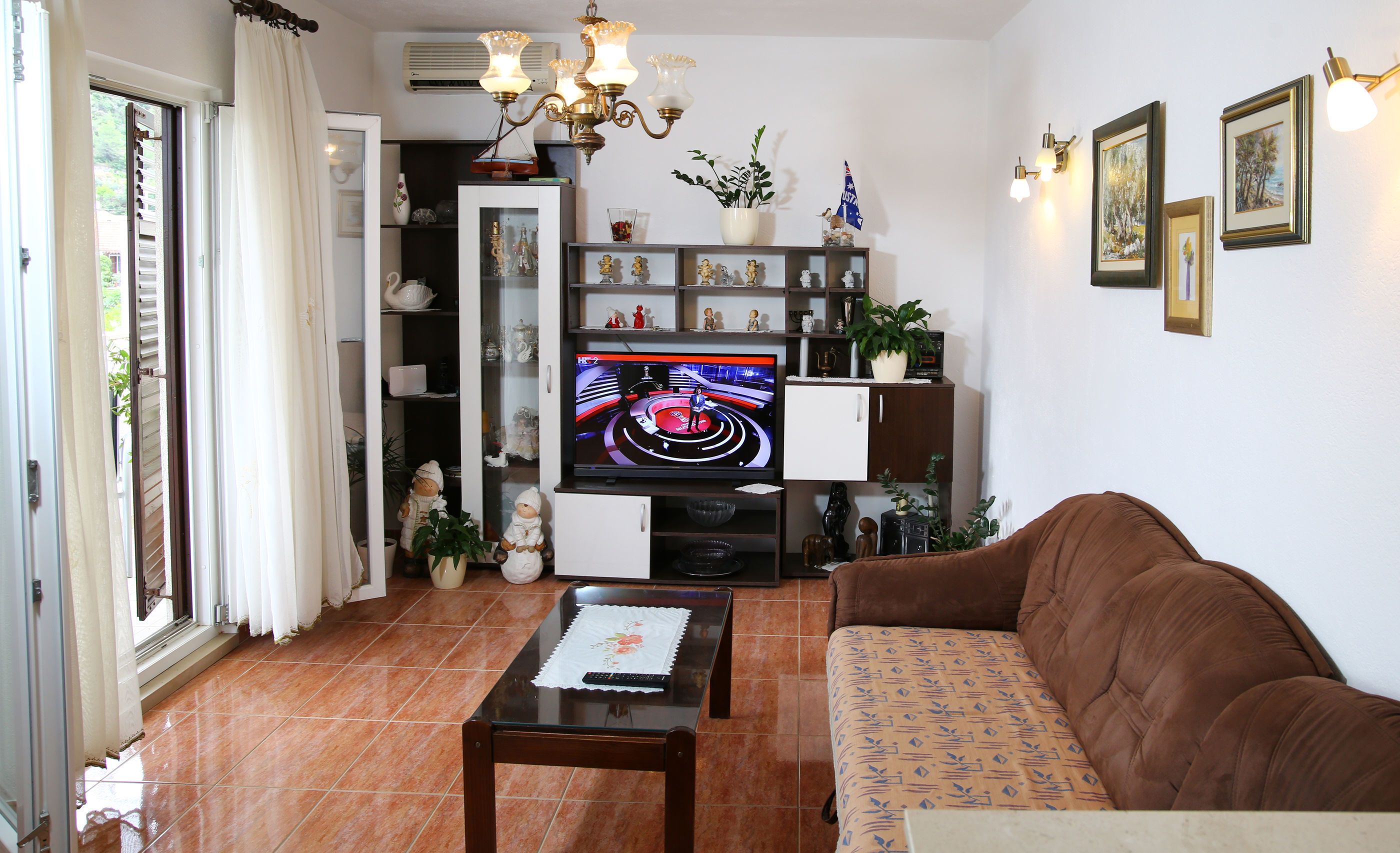 Un salón con televisor, sofá y diversos objetos decorativos.