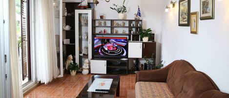 Un salón con televisor, sofá y diversos objetos decorativos.