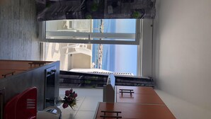 A room with a large window, a desk, a chair, and a small table with a vase of flowers. - Apartments Suzana (Jakisnica)