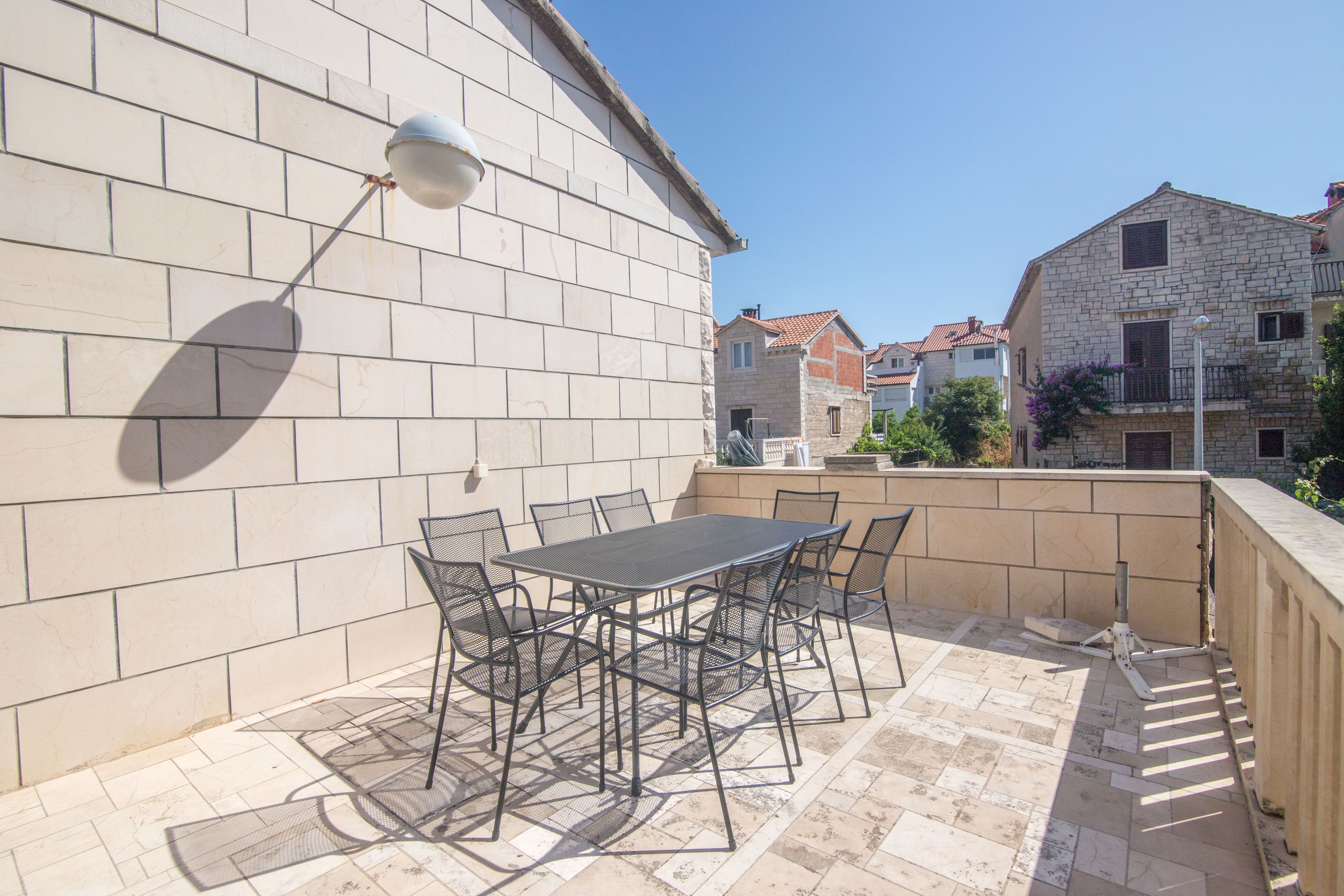 A patio with a table and chairs, a lamp, and a view of neighboring buildings.