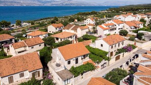 A coastal village with traditional stone buildings, terracotta roofs, and a view of the sea and mountains. - Apartment Jerka (Supetar)