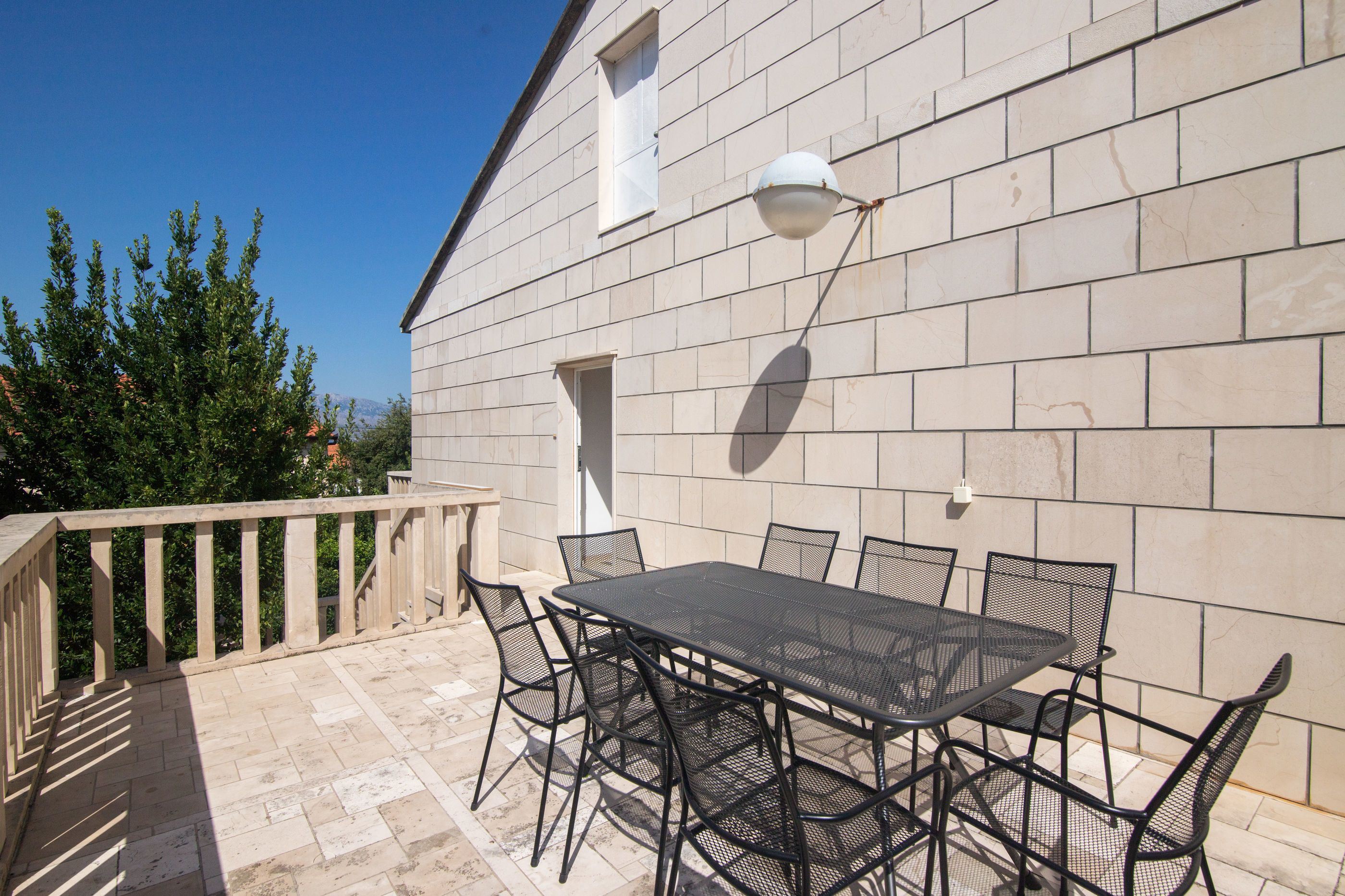 Eine Terrasse im Freien mit Tisch, Stühlen, einer Brüstung und einer Steinmauer.