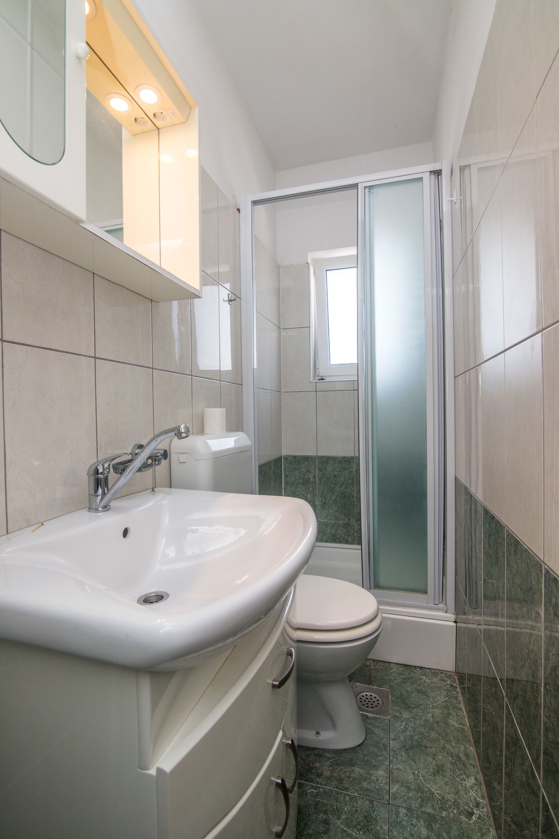 Une salle de bain avec un lavabo blanc, des toilettes et une douche à parois de verre.