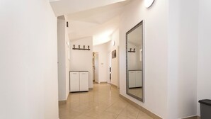 A hallway with a large mirror, a white door, and a trash bin. - Apartments Ivan by the sea (Vodice)