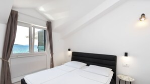 A bedroom with a bed, a window with curtains, a nightstand, and a wall-mounted light. - Apartments Ivan by the sea (Vodice)