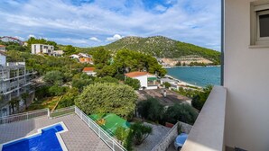 Ein Balkon mit Blick auf eine Küstenstadt, einem Swimmingpool und einem Berg im Hintergrund.