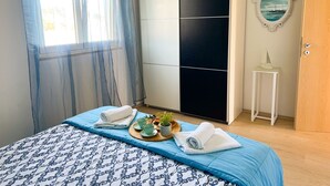A bedroom with a bed, a wardrobe, a small table with a plant, and a door. - Apartment Natasa (Vinisce)