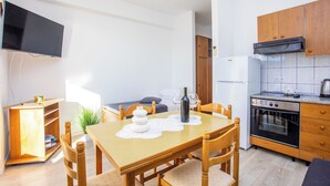 A compact kitchen with wooden cabinets, a built-in oven, and a dining area with a table and chairs.