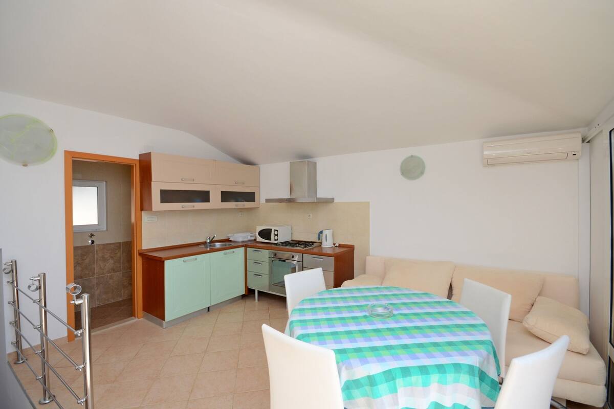 A compact living space with a kitchenette, a dining area with a checkered tablecloth, and a sofa.