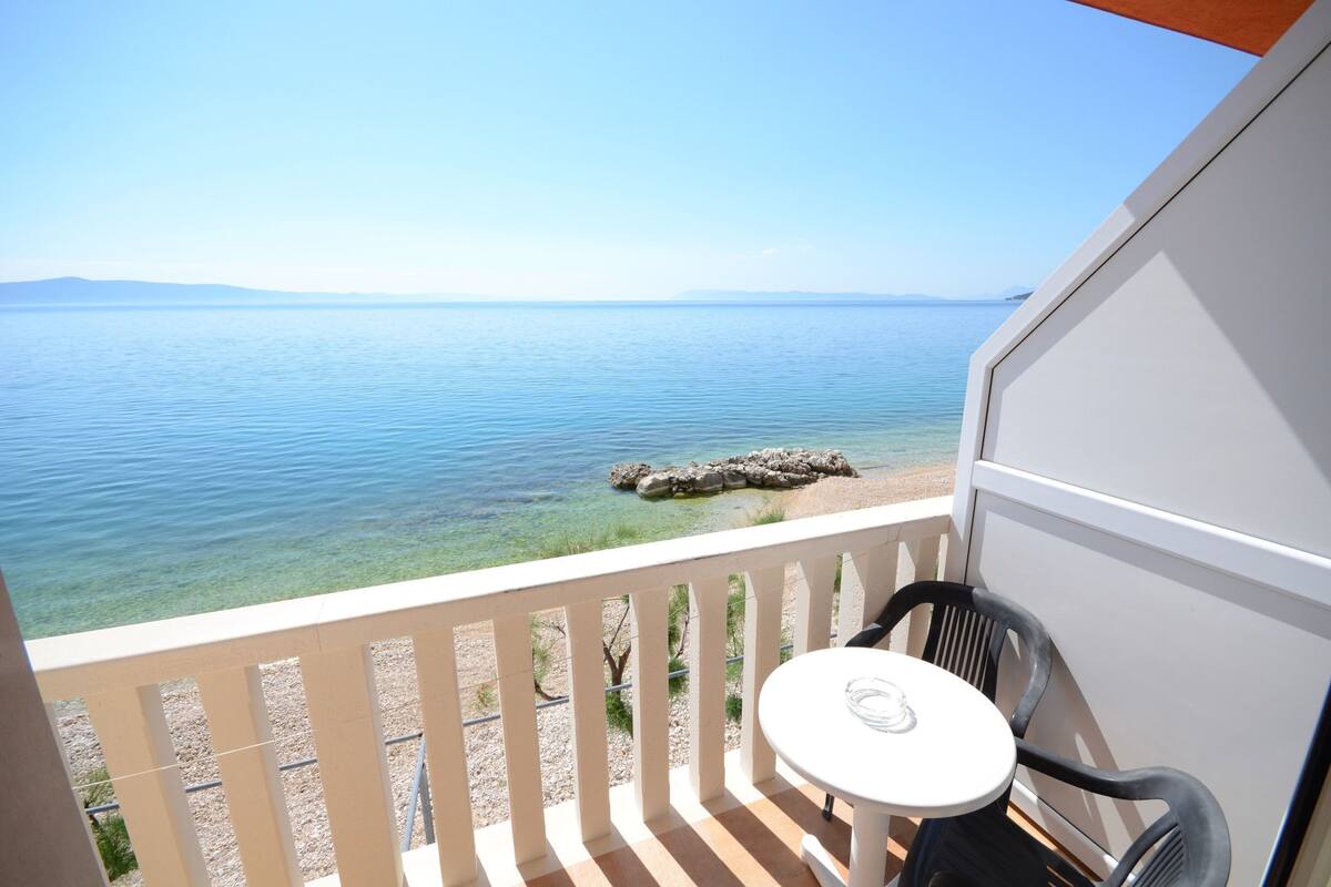 A balcony with a clear view of the sea and a rocky shoreline.