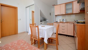 Una cocina compacta con armarios de madera, una mesa de comedor con sillas y una pequeña zona de preparación.