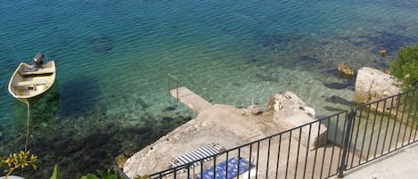 A boat docked at a pier with clear water, a concrete staircase, and a metal railing.