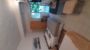 A compact kitchen with a built-in oven, a small countertop, and a window overlooking a garden. - Apartment Zeljka (Seget Vranjica)