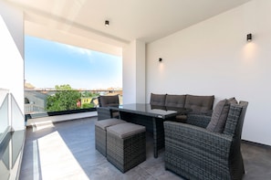 Ein moderner Balkon mit Glastisch und Korbmöbeln, der einen Blick auf die Stadt bietet.