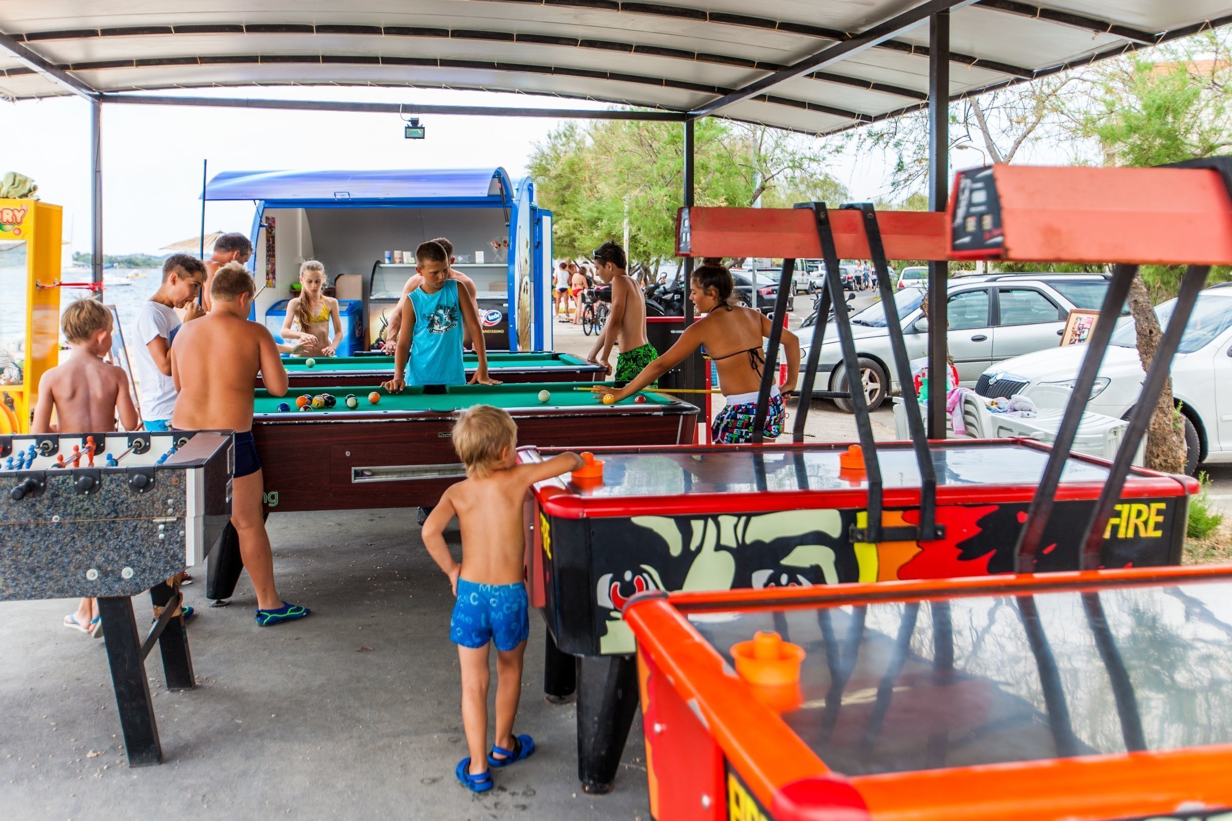 A covered outdoor area with pool tables and foosball tables.