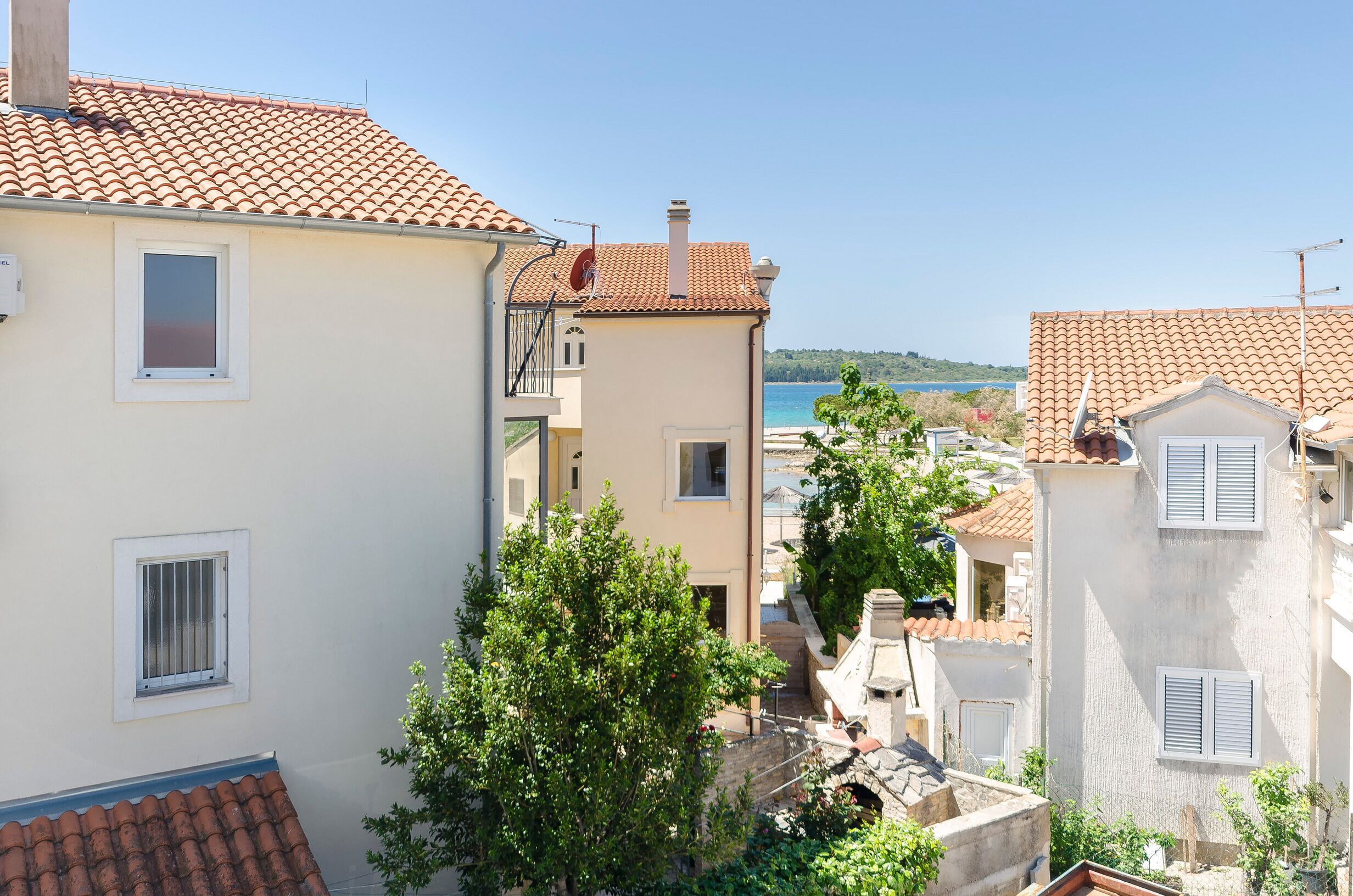 Una zona residenziale sul lungomare, con tetti in tegole di terracotta, cielo azzurro e vista sul mare.