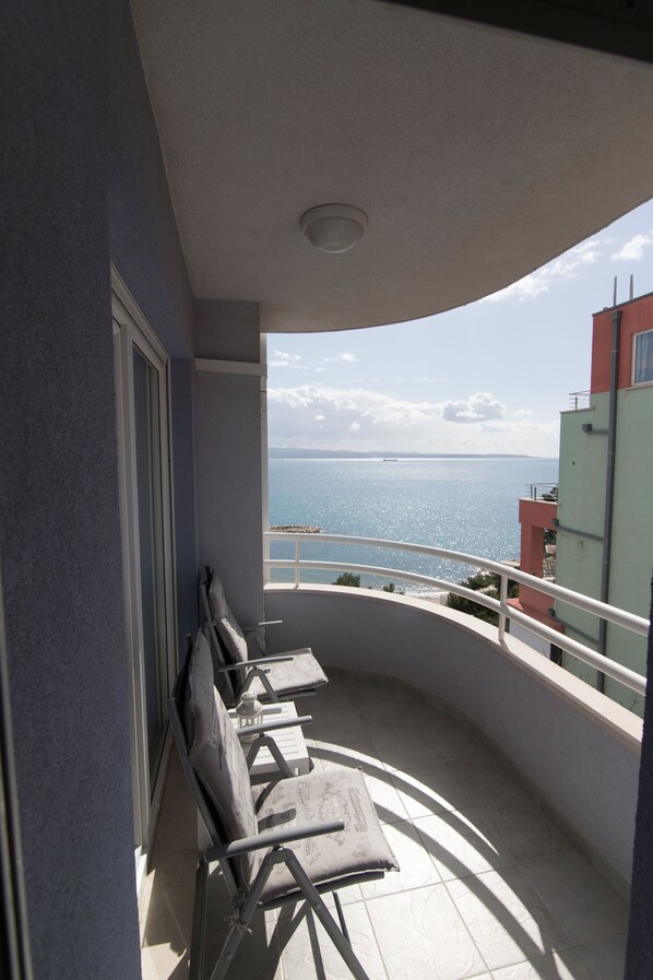 Enjoy the serene view from this balcony with a row of four chairs and a small table.