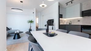 Una cocina moderna con una isla grande, iluminación colgante y una zona de comedor con sillas grises.