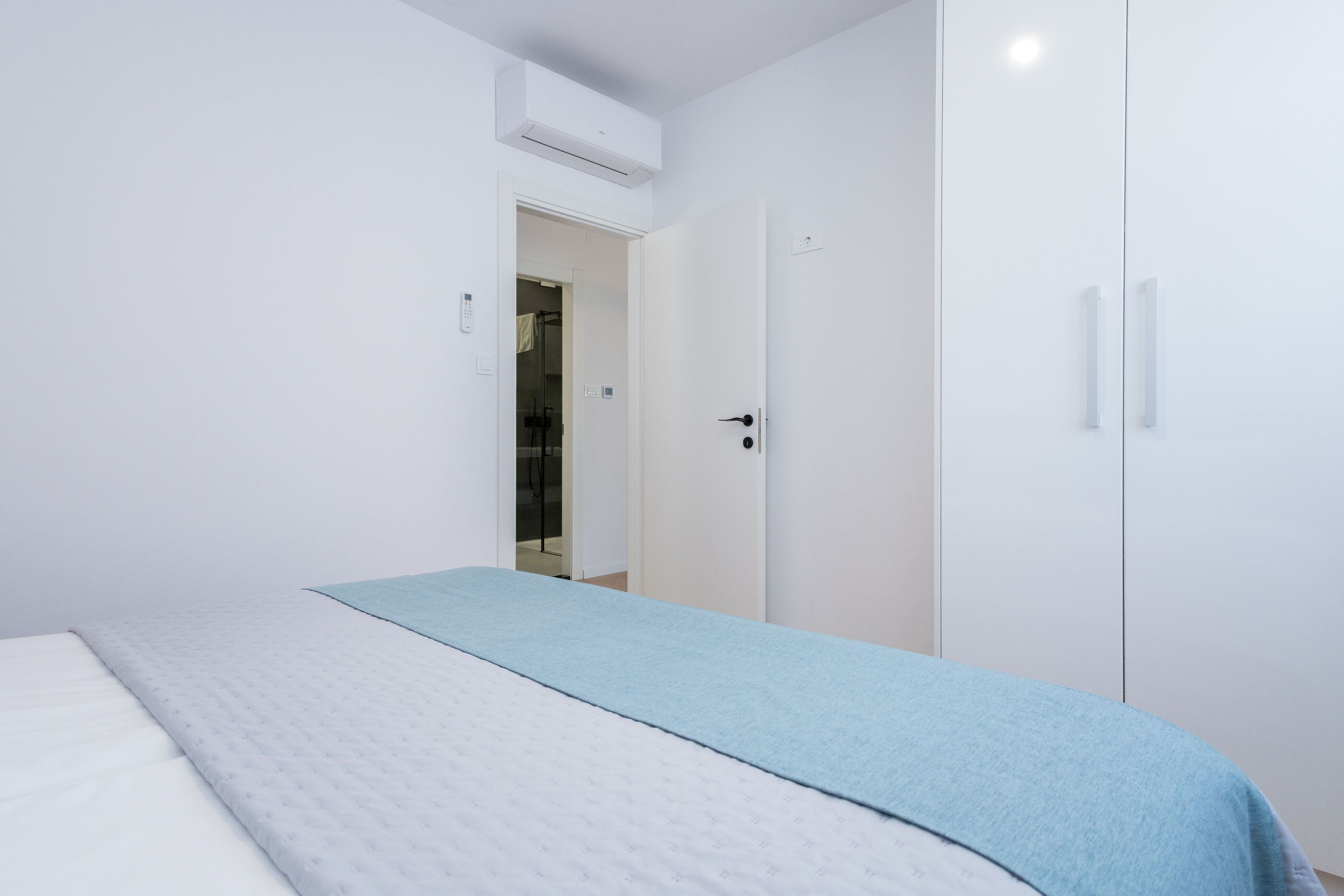 A bedroom with a bed, a wardrobe, and a door leading to a bathroom.
