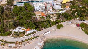 Vista aérea de una zona costera con playa, edificios y un mar azul cristalino.