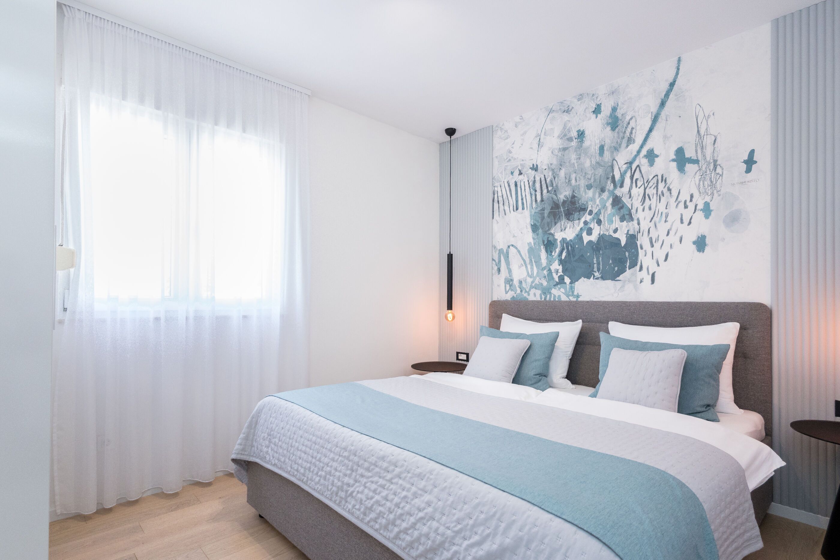 Une chambre moderne avec un grand lit, une table de chevet et une lampe fixée au mur.