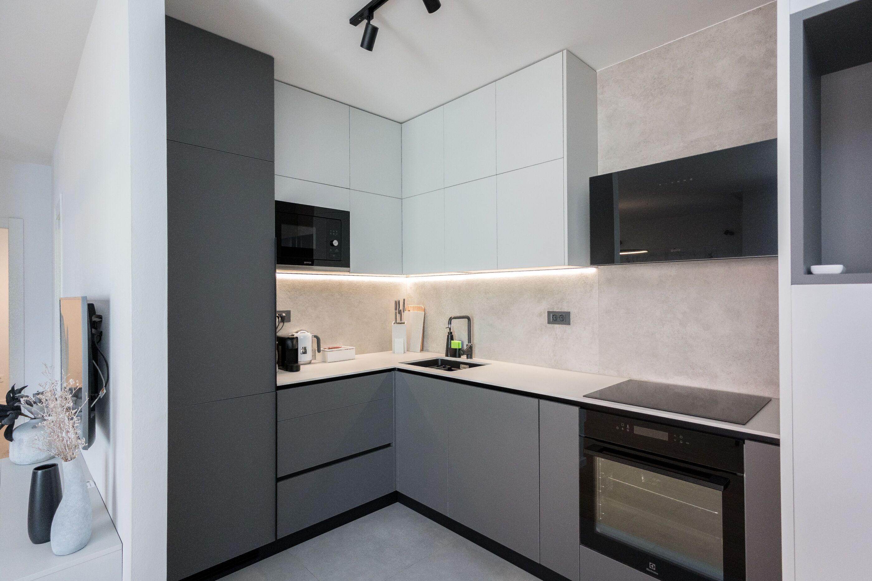 A modern kitchen with grey cabinetry, a built-in microwave, a dishwasher, and a sleek countertop.
