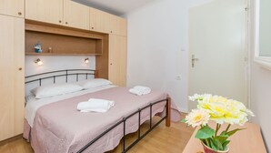 Une chambre à coucher avec un lit, une armoire en bois, une table de chevet et un vase rempli de fleurs.