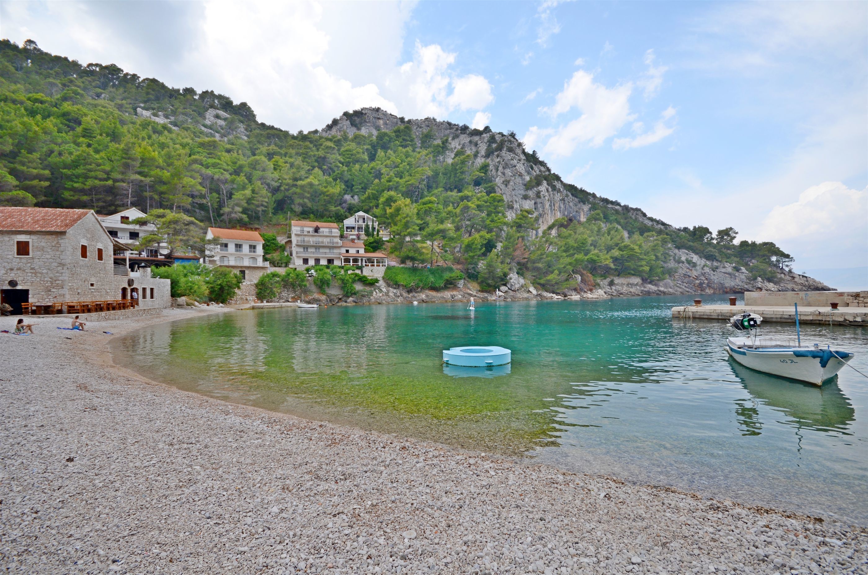 A pebble beach with houses and a boat.