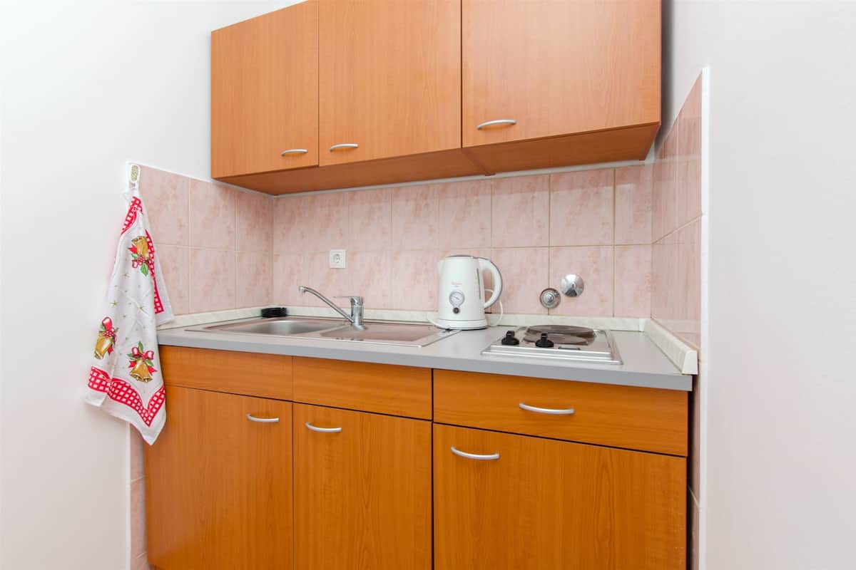 A kitchen with wooden cabinets, a sink, and a kettle.
