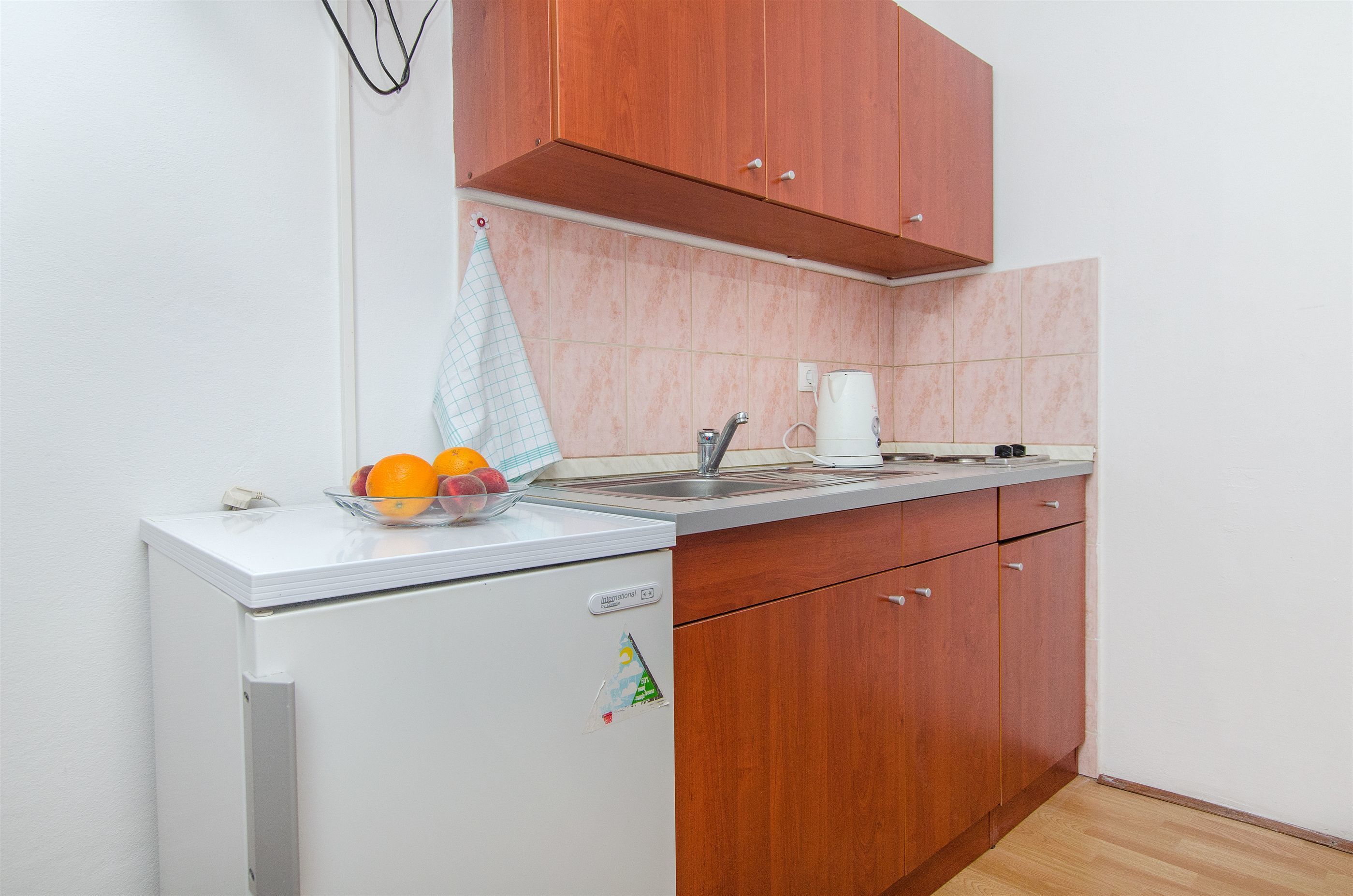 A compact kitchen with wooden cabinets, a white refrigerator, and a sink.