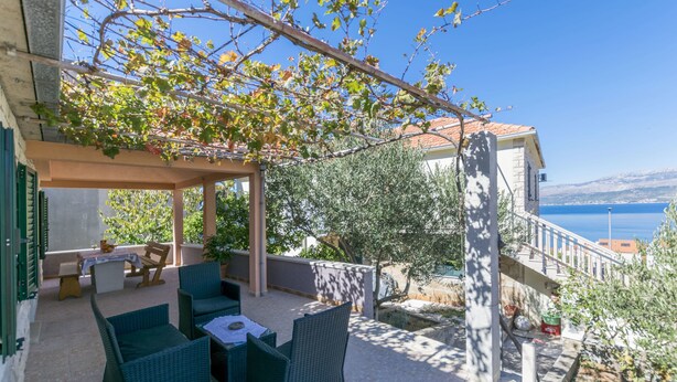 A covered patio with wicker furniture, a table, and a view of the sea. - House Santa Barbara (Postira)
