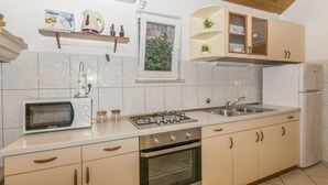 A kitchen with a microwave, stove, oven, sink, and cabinets. - House Santa Barbara (Postira)